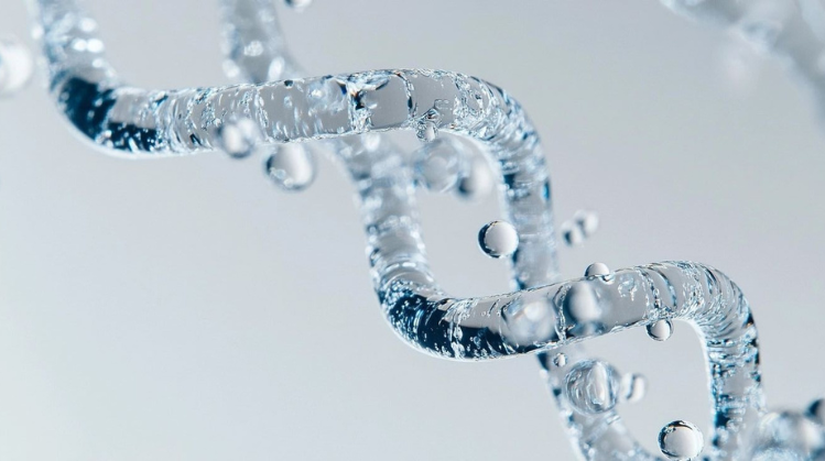 Grafika przedstawia zbliżenie struktury przypominającej podwójną helisę DNA wykonanej z przezroczystej substancji przypominającej wodę.
